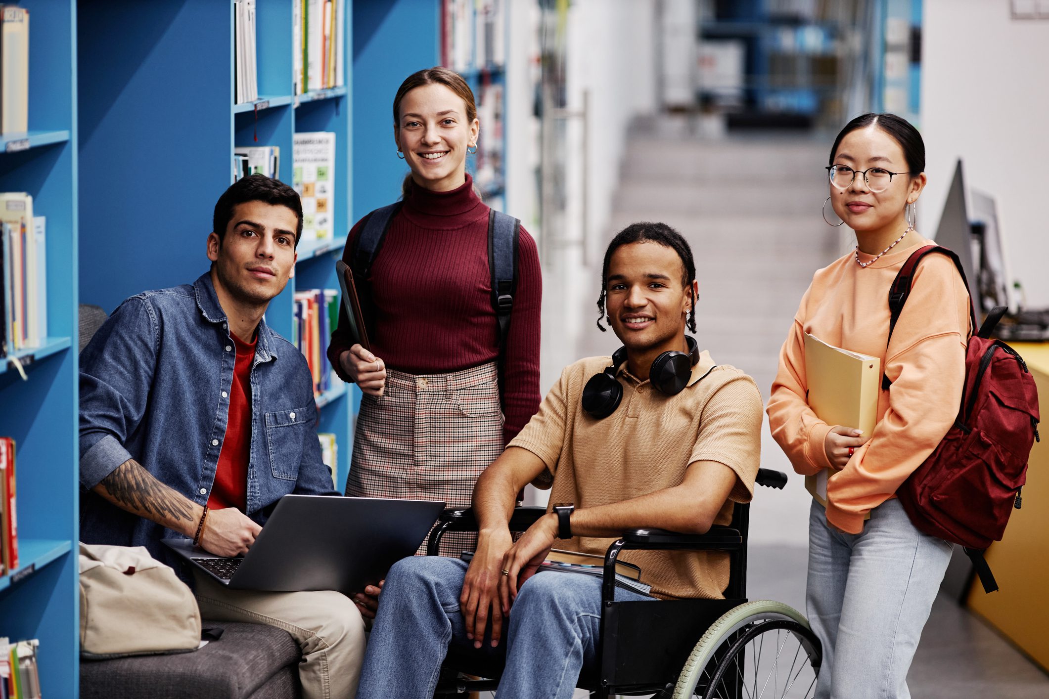 Diverse group of students with young man in wheelchair in college