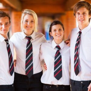 Four young professionals in white shirts and striped ties smiling indoors.