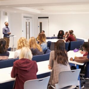 A man giving a presentation to an attentive classroom audience.