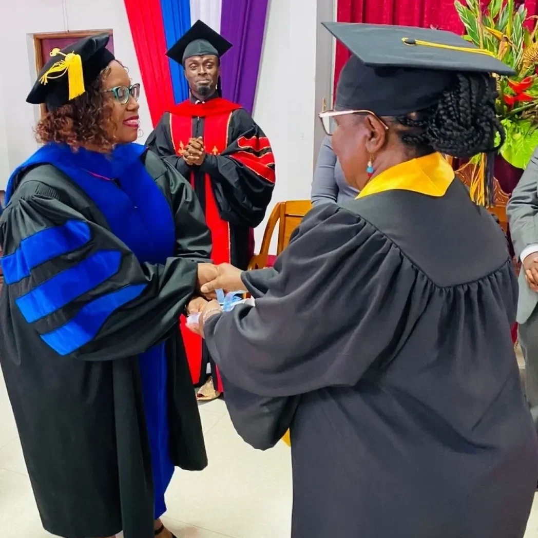 Graduates in gowns shaking hands at ceremony.